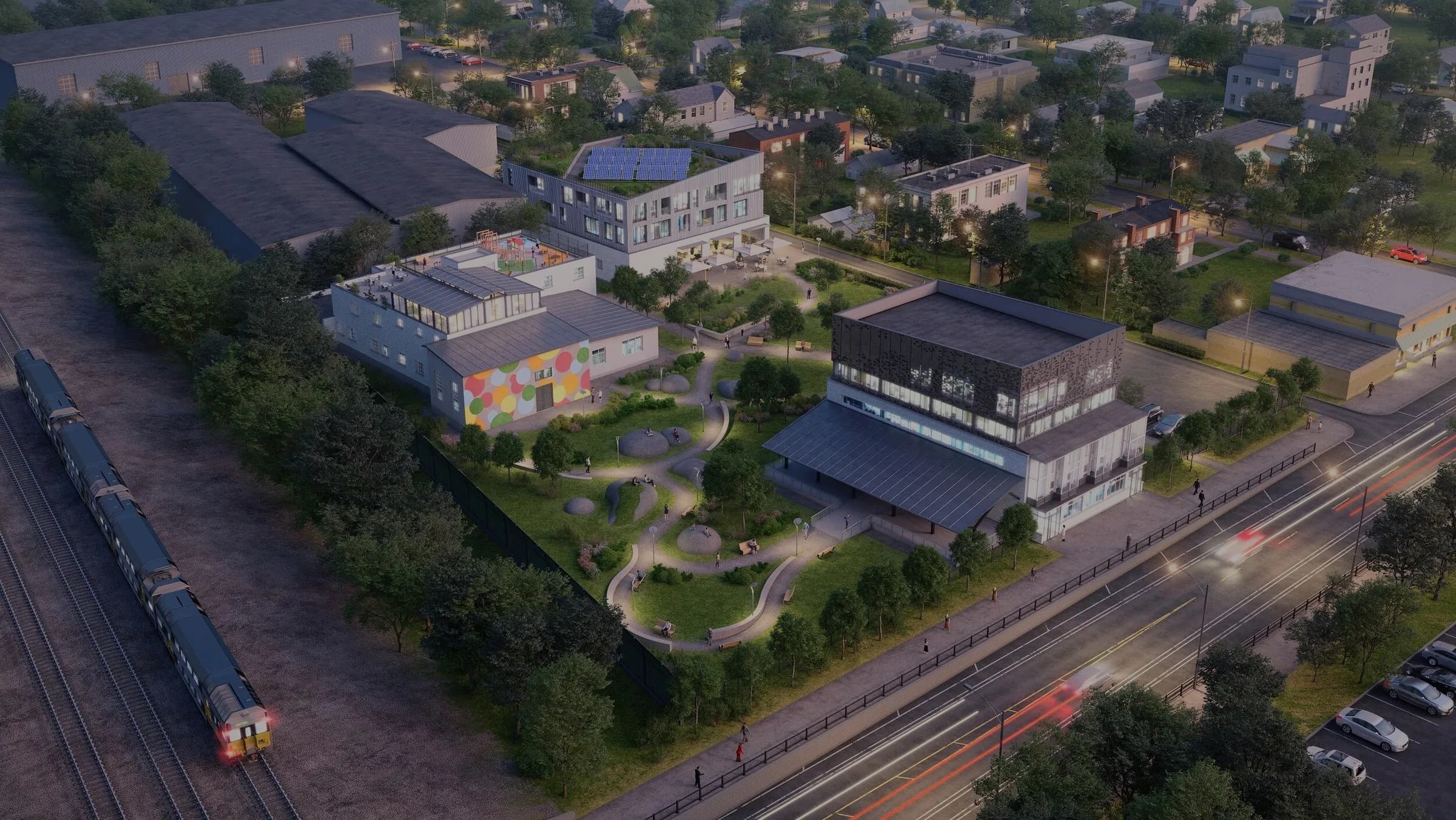 Dusk aerial render of a BLDG Projects mixed-use campus with a landscaped park, set between a Chicago rail line and an arterial street
